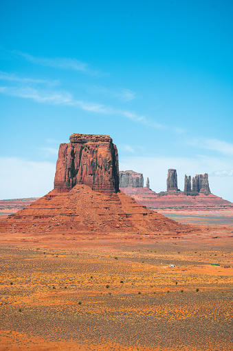 Towering sand stone buttes seen at Monument Valley during a crisp and fresh summer day with blue sky and light clouds. Located on the Arizona and Utah, USA.