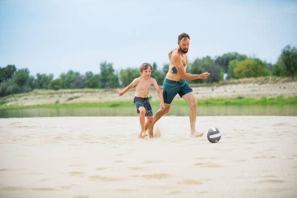 istock Father playing football with his son at the beach 1456990921