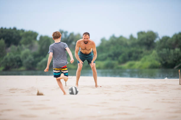 istock Father playing football with his son at the beach 1456991122