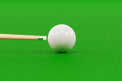 Snooker cue and white pool ball over green pool table. Front view. Horizontal composition with copy space. Snooker concept.