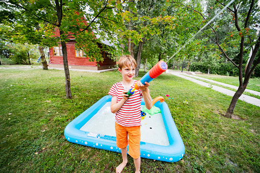 Boy playing with toy water gun at back yard