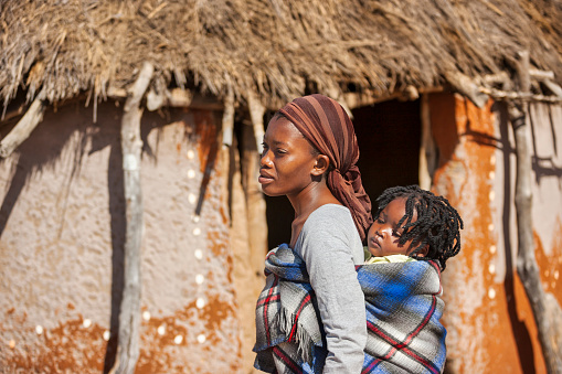 village african mother carrying her child in a blanket in the back