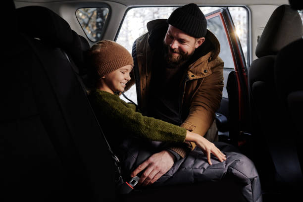 istock Dad fastening his daughter with seat belt before trip 1457004704