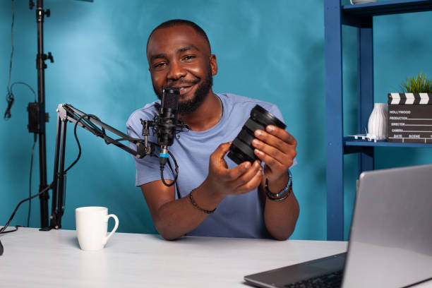 istock Smiling african american techology reviewer presenting dslr zoom lens features 1457005547