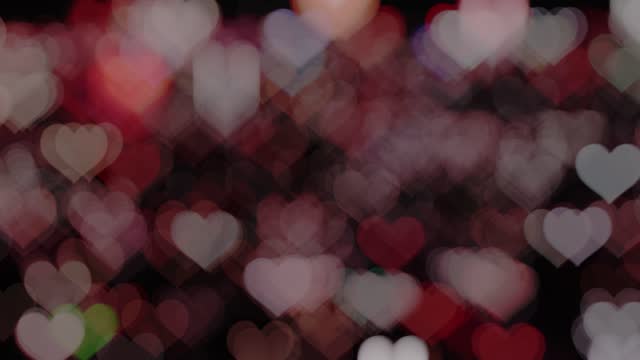 Glowing blur heart shaped lights sparkling on dark background