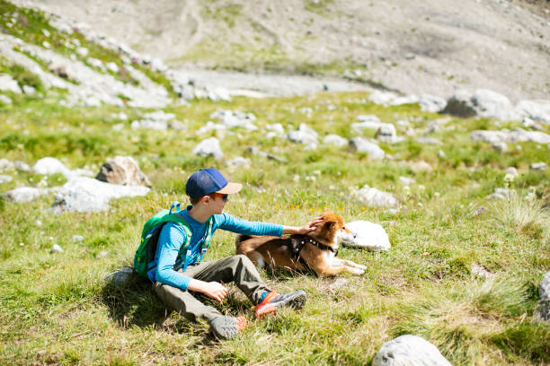 istock Boy sitting with his dog while trekking in mountains 1457010617