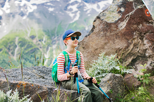Little boy resting while hiking in mountains