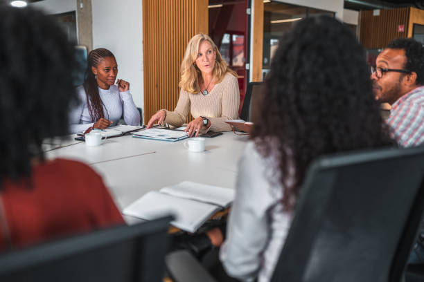 istock Mid Adult Work Colleagues Talking Business at a White Table 1457011415