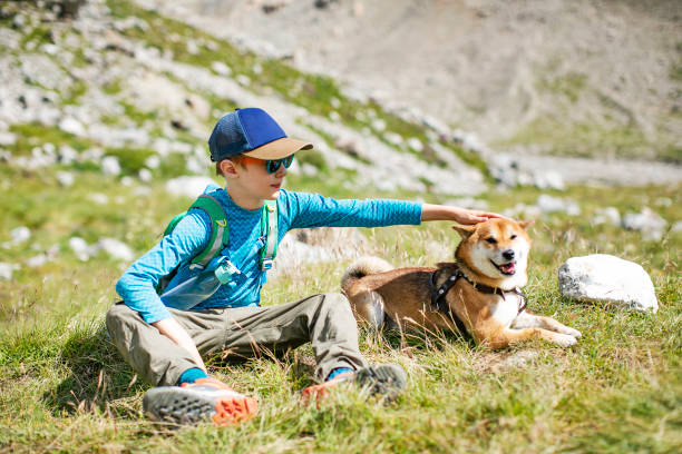istock Boy sitting with his dog while trekking in mountains 1457012485