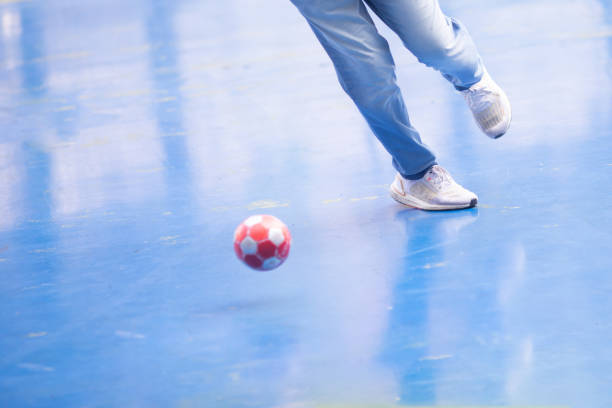 selektiver fokus auf den fuß des futsalspielers mit verschwommenem rotem ball. indoor-fußball-sporthalle. futsal-boden. - soccer field soccer single line field stock-fotos und bilder