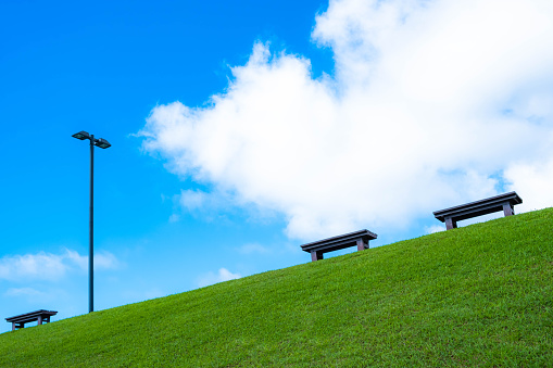 Benches on small hill with blue sky and white cloud in the background