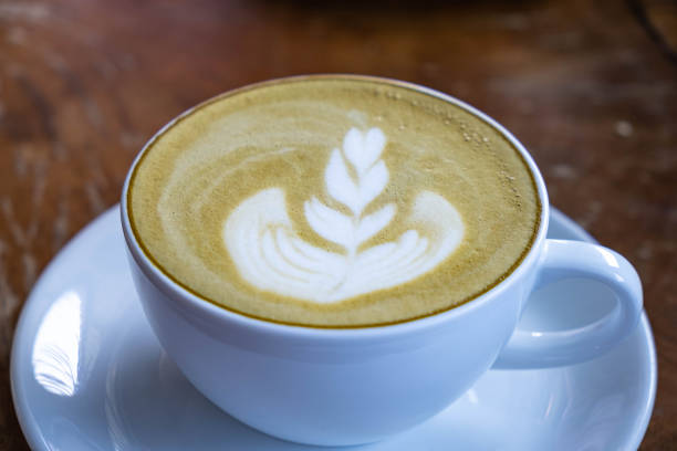 Green tea latte in white cup on wooden desk