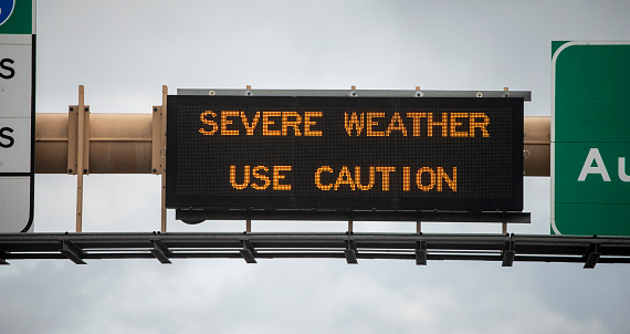 Digital sign at freeway stating Severe Weather Use Caution with wet freeway and traffic.