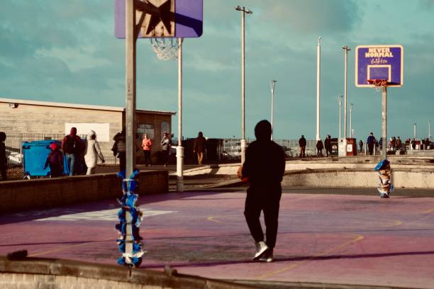Person playing basketball solo. Captured on Brighton Beach in Brighton on the 26th January 2023. Brighton is a seaside resort and one of the two main areas of the City of Brighton and Hove in the county of East Sussex, England.