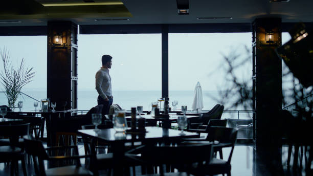 Handsome man silhouette spending time in classic dark cafe guest hall interior