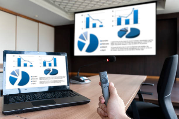 istock Businessman hand hold remote control with slide presentation on display projector screen and laptop in meeting room 1457024959