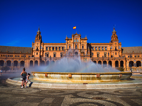 Plaza de Espana, Seville, Spain - July 08 2019 : Tourists admire the magnificent water fountain middle of the circular courtyard where once used as a setting for a Star Wars film.