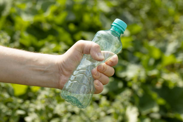 istock Hand holding crumpled empty plastic bottle in the park 1457030185