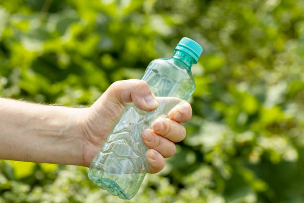 istock Hand holding crumpled empty plastic bottle in the park 1457030954