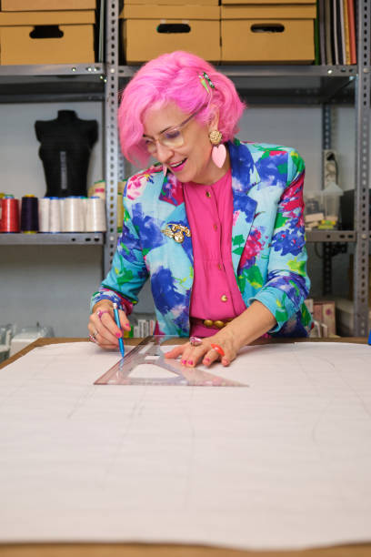 istock Dressmaker with pink hair and colorfull clothes drawing sewing patterns. 1457030955