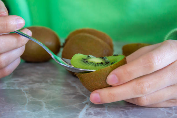 istock Woman eating kiwi fruit 1457034073