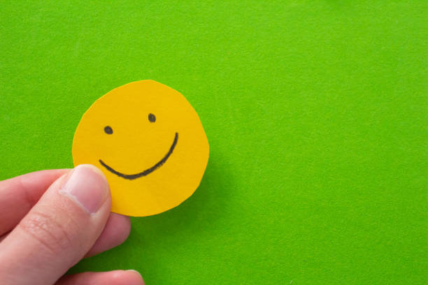 istock Hand holding paper with smiley face drawn on it 1457034266
