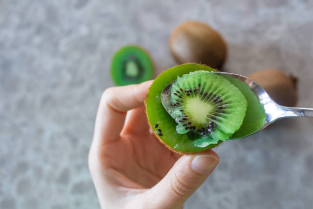 Woman eating kiwi fruit Woman eating kiwi fruit. Healthy lifestyle concept. Top view, closeup photo. kiwi fruit stock pictures, royalty-free photos & images