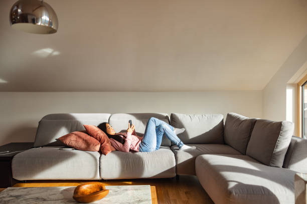 istock Beautiful Asian Female Using A Smart Phone While Relaxing On The Sofa 1457034444