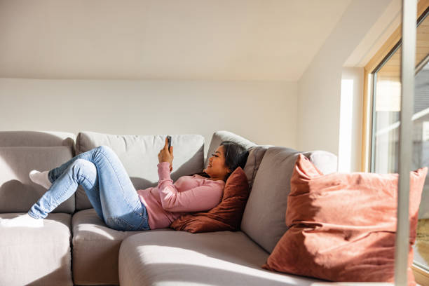 istock Beautiful Asian Female Using A Smart Phone While Relaxing On The Sofa 1457034592