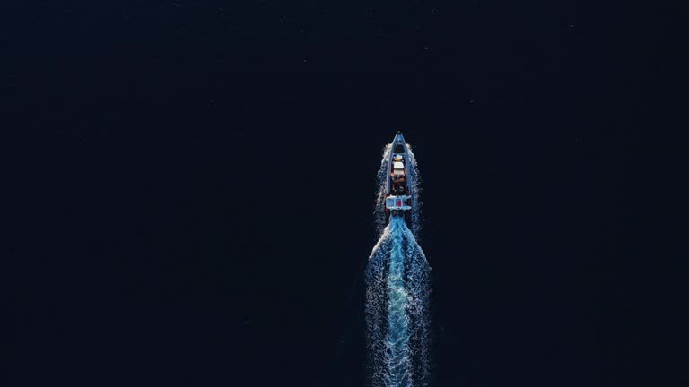 Top down view of power boat motoring across the smooth dark ocean on golden afternoon