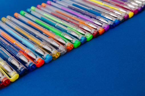 A set of gel pens on a blue background.