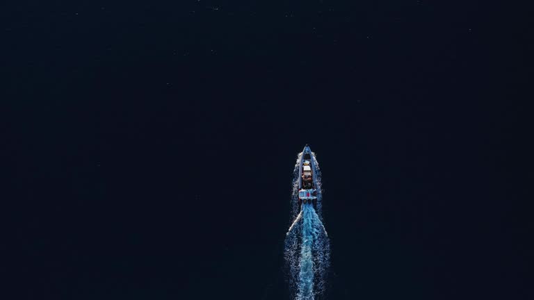 Top down view of power boat motoring across the smooth dark ocean on golden afternoon