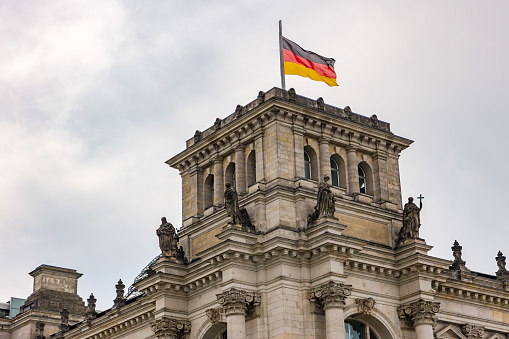 The German flag on the ornate tower of the Reichstag building in the government district in Berlin, Germany