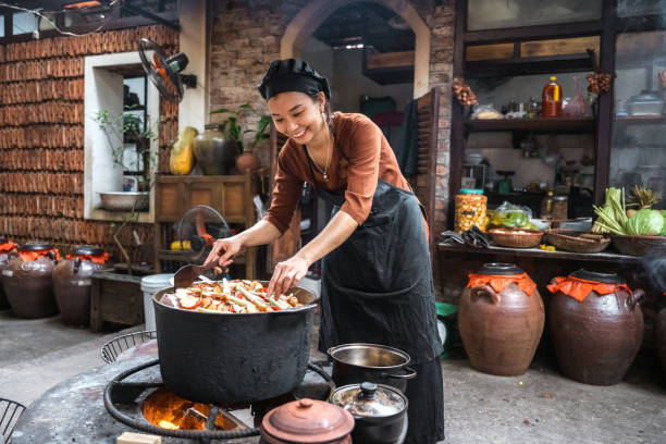 young vietnamese female chef cooking on open fire in restaurant
