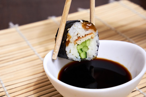 Sushi rolls and soy sauce. Chopsticks take sushi