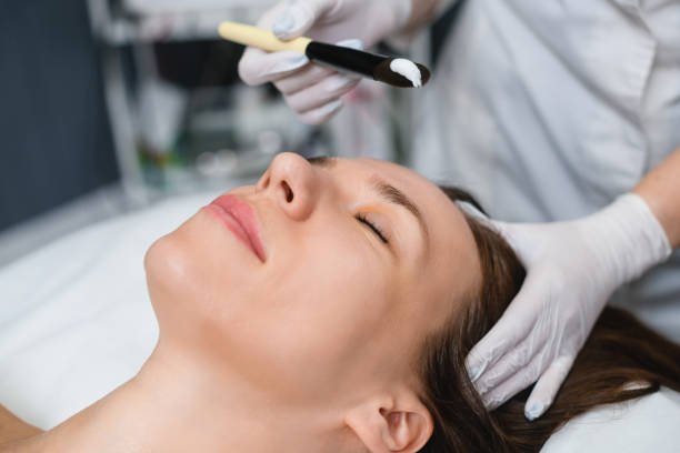 istock Cosmetologist put white mask at female face 1457048408