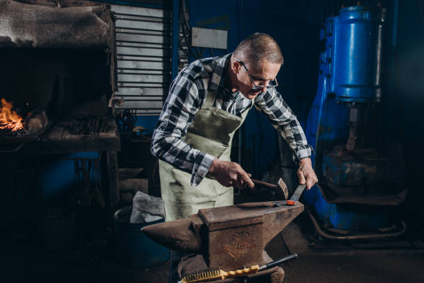 istock The blacksmith manually forging the red-hot metal on the anvil in smithy. 1457048993