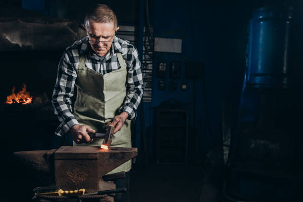 istock The blacksmith manually forging the red-hot metal on the anvil in smithy. 1457049116