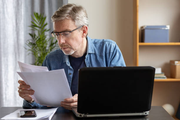 istock White 50 year old businessman working with documents at home office using laptop 1457049530