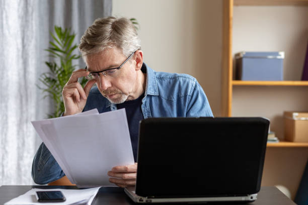 istock White 50 year old businessman working with documents at home office using laptop 1457049548
