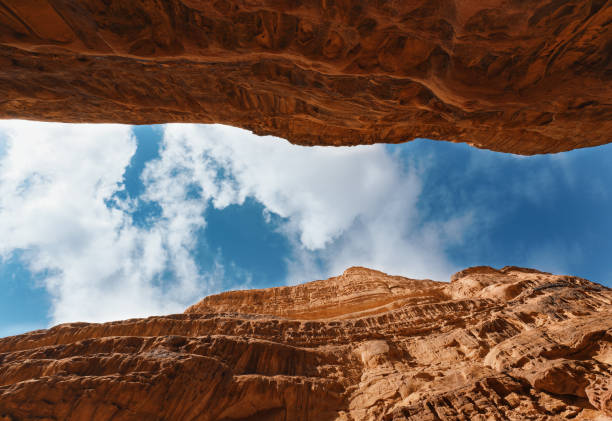 istock Looking up red sandstone canyon in Wadi Rum desert, blue sky with clouds above 1457049570