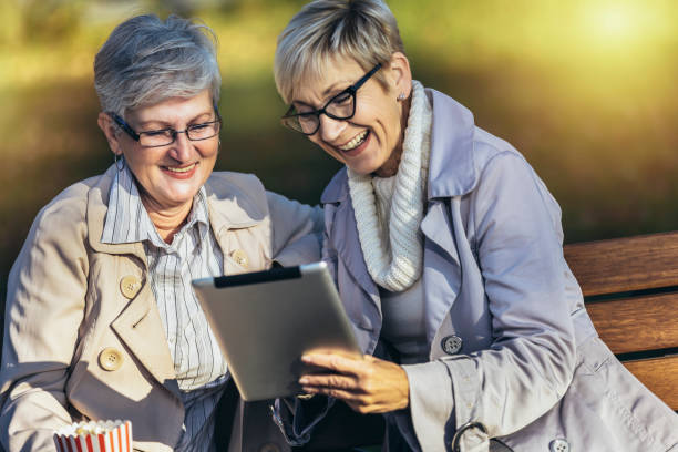 istock Two senior female friends using digital tablet in the park 1457050255