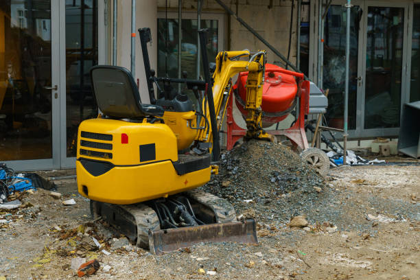 istock Small yellow excavator and concrete mixer at a construction site. 1457050409
