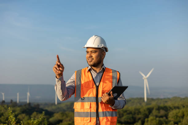 istock Engineer India man working with tablet at windmill farm Generating electricity clean energy. Wind turbine farm generator by alternative green energy. Asian engineer checking control electric power 1457051003