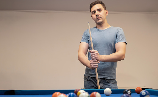 a man holds his hand on a pool table, plays snooker or prepares to shoot billiard balls, port game snooker billiards, billiard balls, play billiards