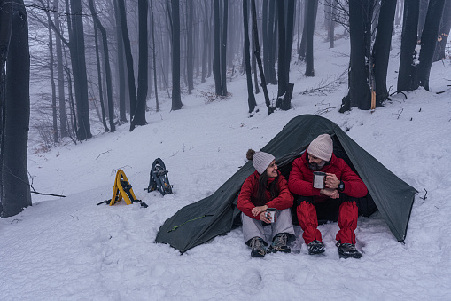 Couple on adventure trip with tent and snowshoes in winter.