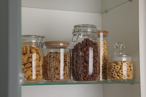 Glass containers with different breakfast cereals on shelf