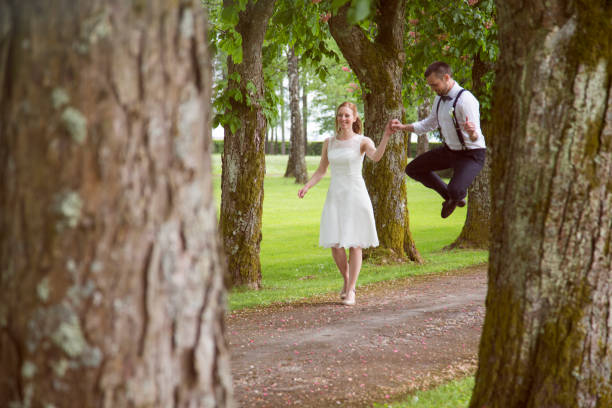 istock Bride and groom walking through treelined path - happy jump 1457060478