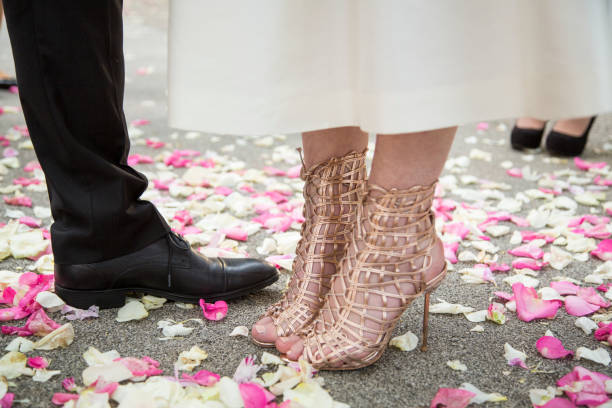 Bride and groom standing on pink and white rose petals. Guests standing in the back.