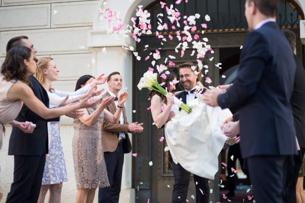 istock Guests throwing rose petals on bride and groom 1457060570